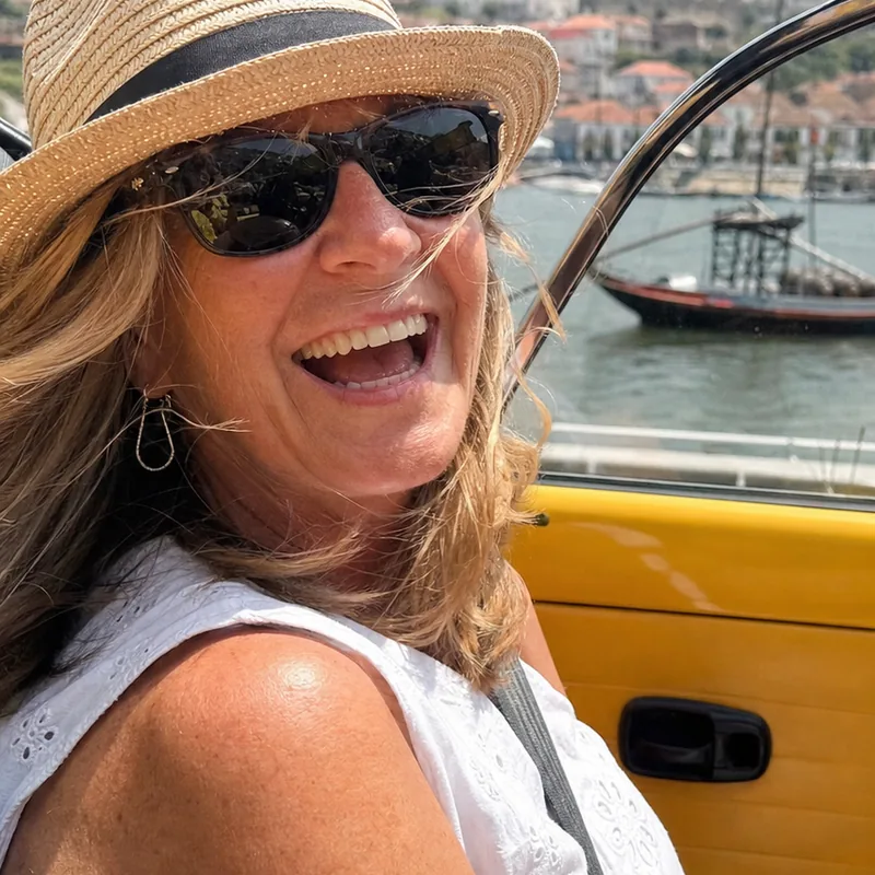 Linda laughing in the back seat of the yellow Beetle with the Douro river behind her